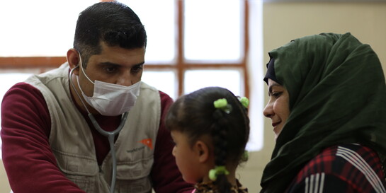 Ein Arzt mit Mundschutz untersucht ein Mädchen im Irak