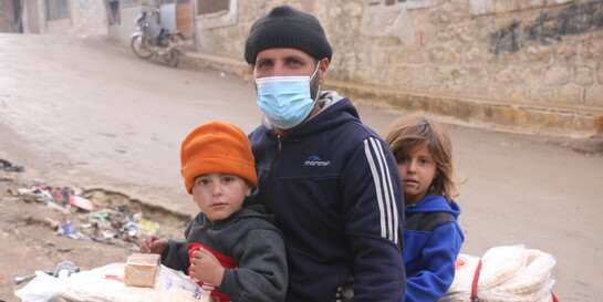 Ein Vater in Syrien transportiert auf einem Motorrad Lebensmittel mit seinen zwei Kindern 