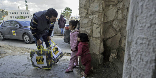Mitarbeiter von Help verteilt Hilfsgüter an Kinder in Syrien