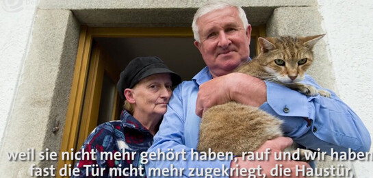 Das Ehepaar Bretzendorfer steht zusammen mit ihrer Katze vor ihrem Haus.