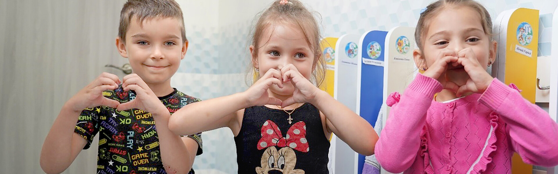 Drei Kinder in der Ukraine formen mit ihren Händen ein Herz