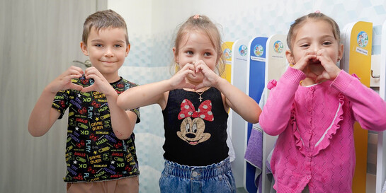 Drei Kinder in der Ukraine formen mit ihren Händen ein Herz