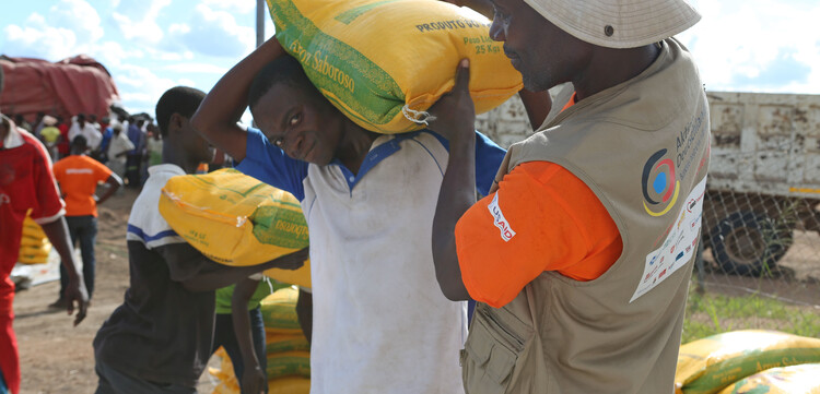 Ein Helfer gibt einem Mann in Mosambik Hilfsgüter 
