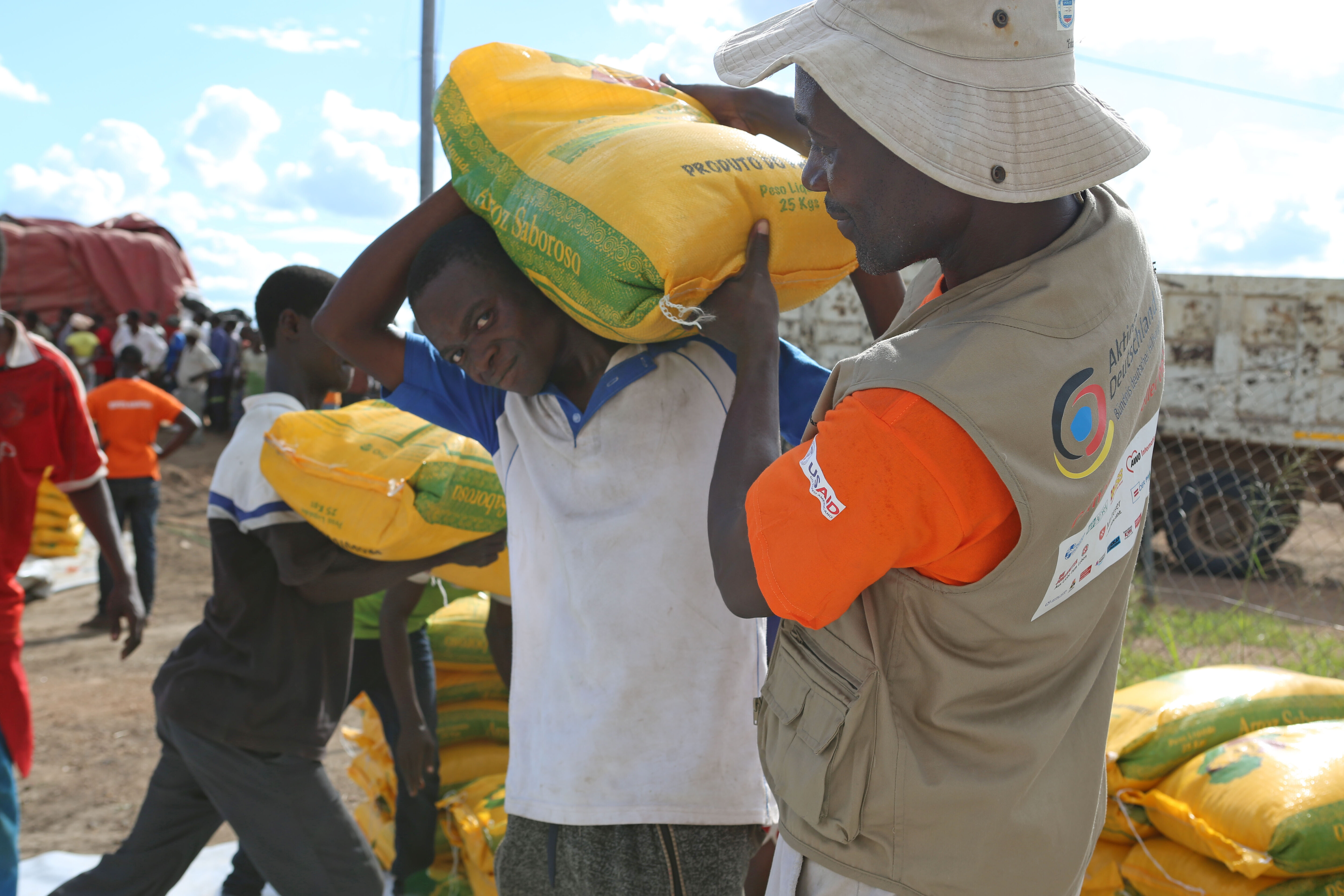 Ein Helfer gibt einem Mann in Mosambik Hilfsgüter 