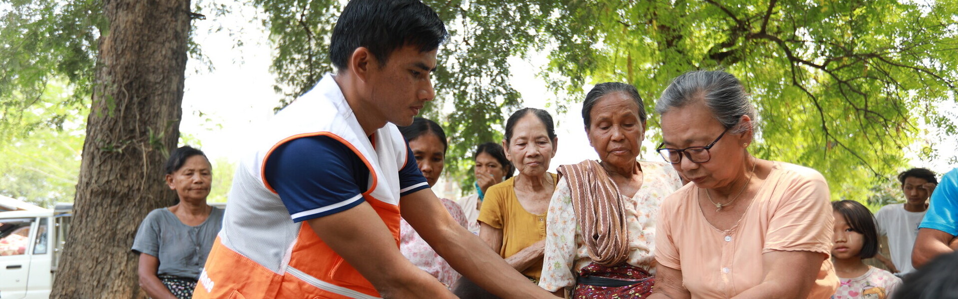 Ein Helfer von World Vision überreicht einer Gruppe Frauen in Myanmar eine Hilfslieferung