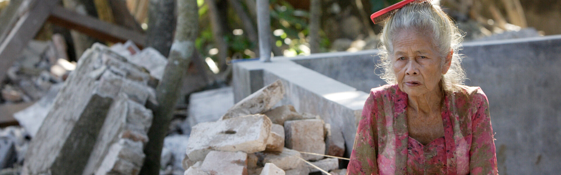 Eine Frau in Indonesien vor den Trümmern ihres von einem Erdbeben zerstörten Hauses (Archivbild)