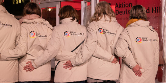 Fünf Mitarbeitende von Aktion Deutschland Hilft zeigen Rücken