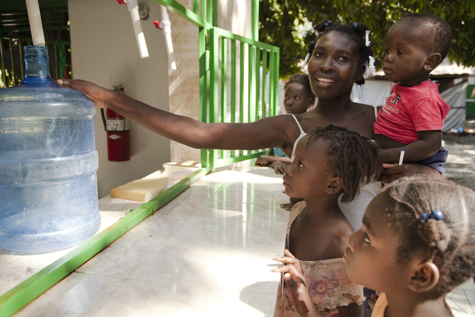 Nach dem Erdbeben in Haiti erhält eine Frau mit ihren Kindern Trinkwasser.