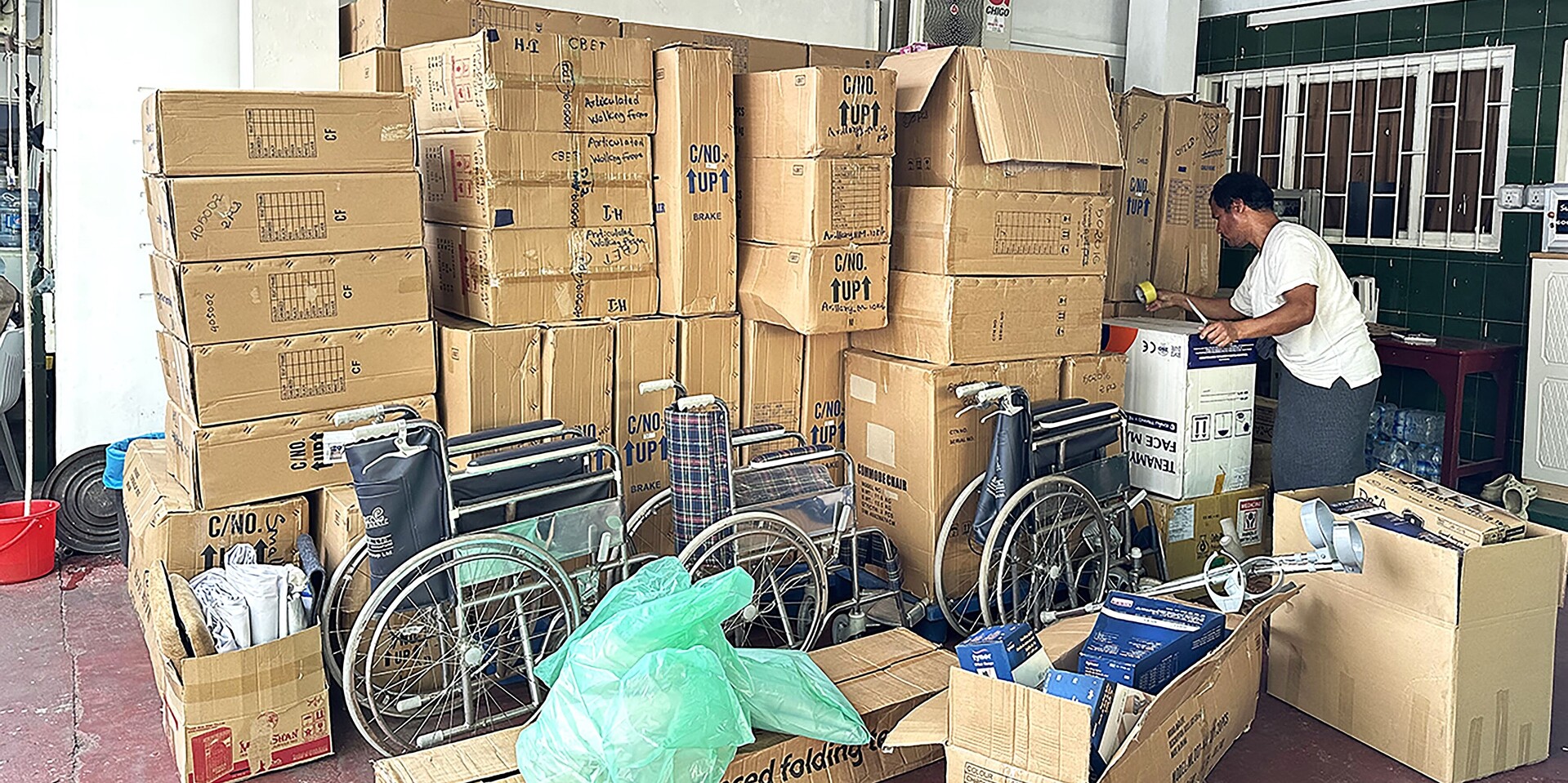 Ein Helfer packt eine Lieferung mit Gehhilfen und Rollstühlen für Verletzte in Myanmar aus