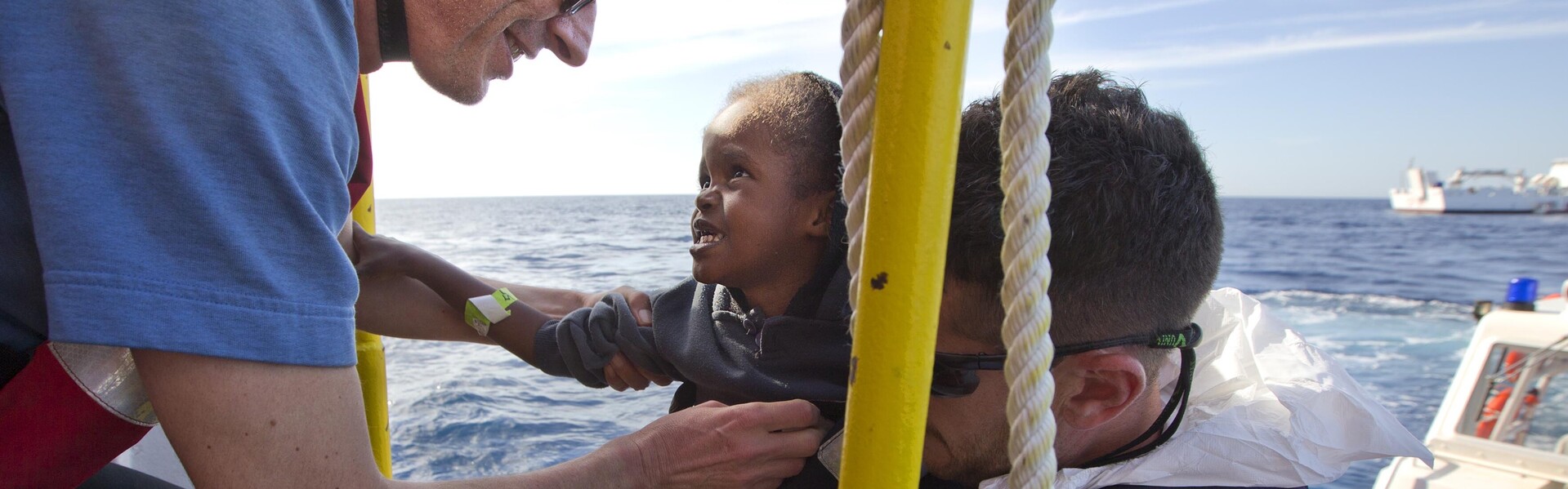 Ein Helfer holt ein Kind an Bord im Mittelmeer