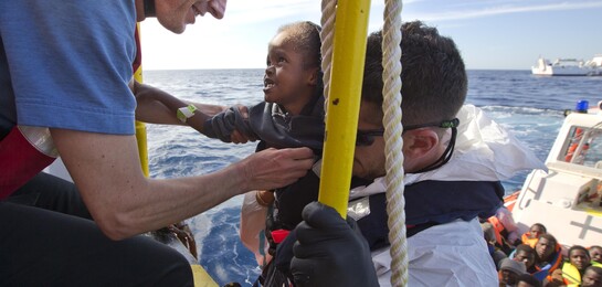 Ein Helfer holt ein Kind an Bord im Mittelmeer