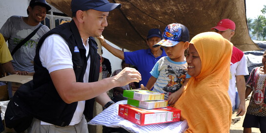 Ein Helfer in Indonesien verteilt Lebensmittel nach der Katastrophe