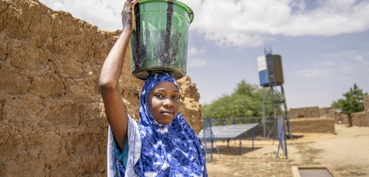 Eine Frau in Somalia trägt einen Eimer voller Wasser auf ihrem Kopf