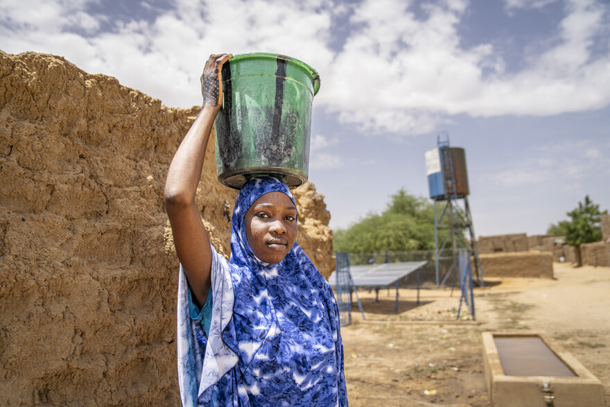 Eine Frau in Somalia trägt einen Eimer voller Wasser auf ihrem Kopf