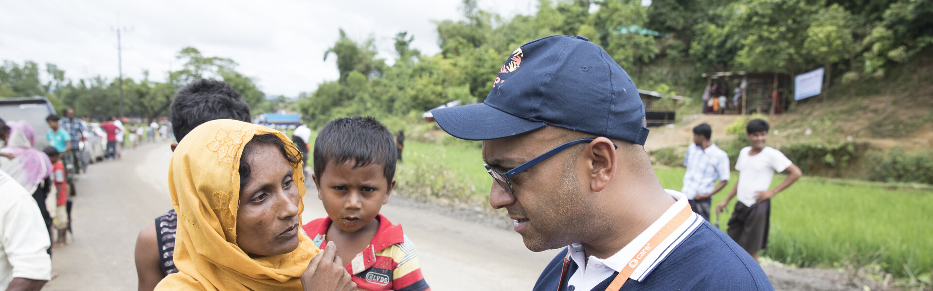 Ein Helfer von Care unterhält sich im Flüchtlingscamp Cox's Bazar in Bangladesch mit einer Mutter, die ihren Sohn auf dem Arm trägt