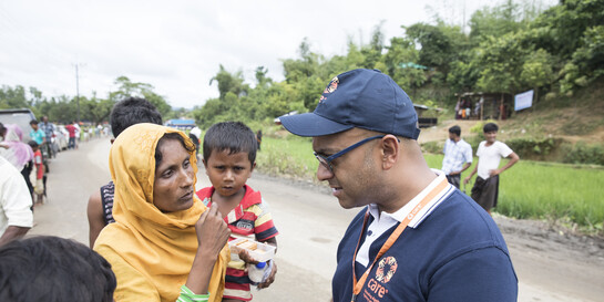 Ein Helfer von Care unterhält sich im Flüchtlingscamp Cox's Bazar in Bangladesch mit einer Mutter, die ihren Sohn auf dem Arm trägt