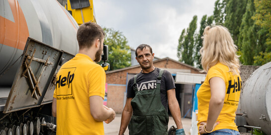 Helfer:innen von Help - Hilfe zur Selbsthilfe sprechen mit einem Landwirt