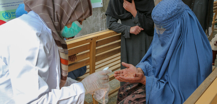 Eine Helferin verteilt Desinfektionsmittel an Frauen in Afghanistan Eine Helferin verteilt Desinfektionsmittel an Frauen in Afghanistan
