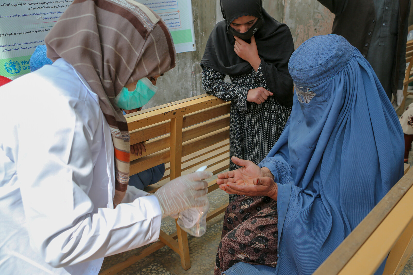 Eine Helferin verteilt Desinfektionsmittel an Frauen in Afghanistan