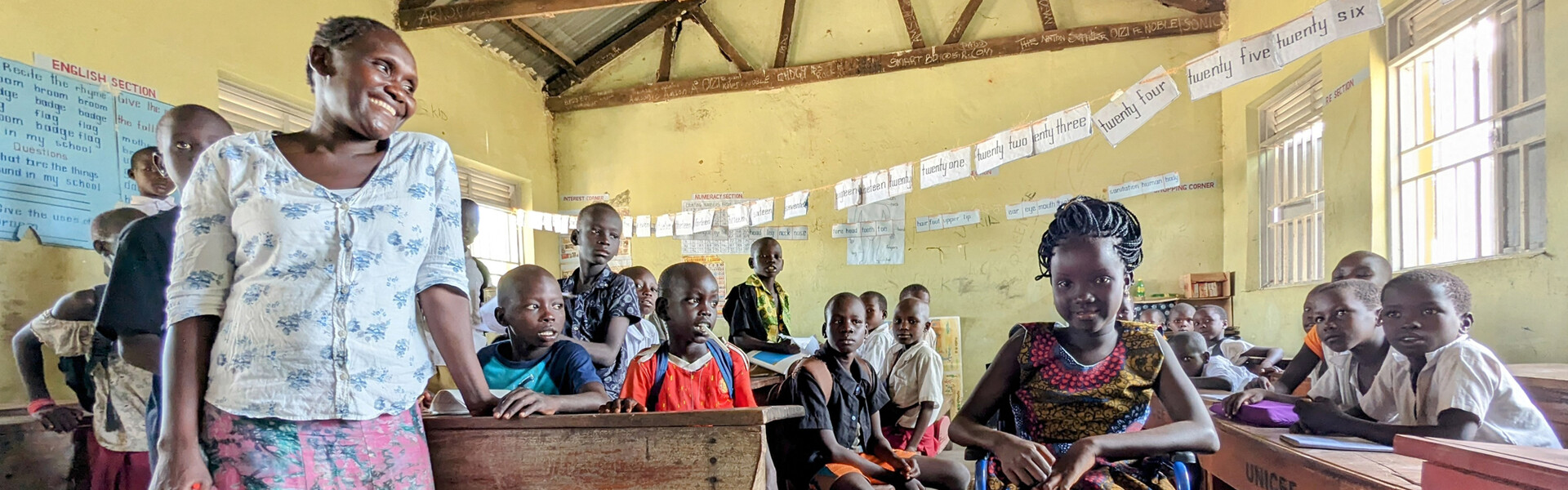 Anai aus dem Flüchtlingslager Rhino Camp in Uganda, die dank eines Rollstuhls von Handicap International die Schule besuchen kann