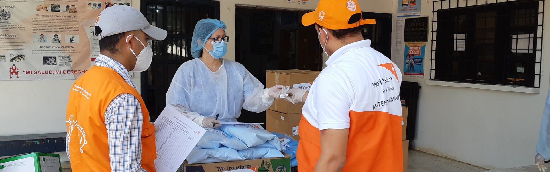 Drei Helfer:innen von World Vision verteilen Medikamente und andere Hilfsgüter (Symbolbild)