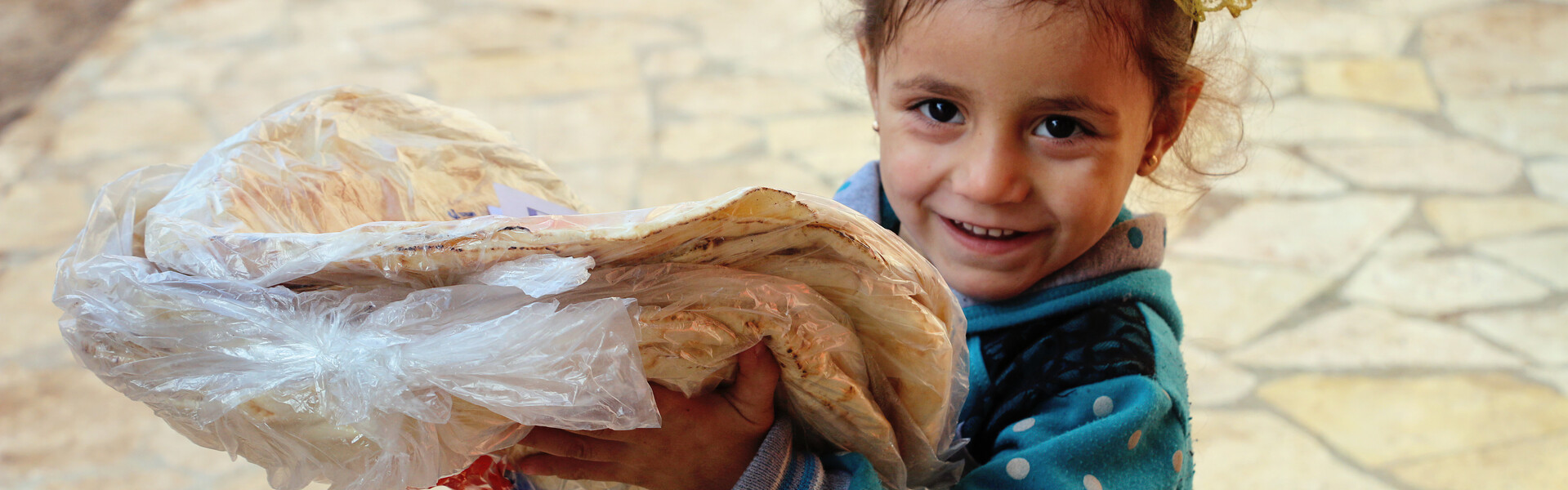 Ein Mädchen aus dem Erdbebengebiet in Syrien hält ein Brot in der Hand