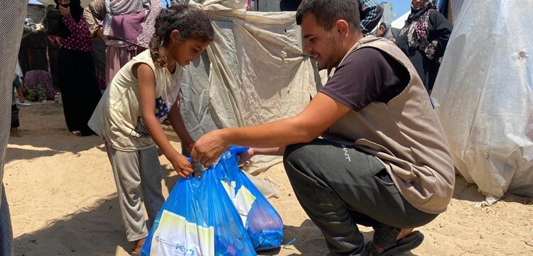 Helfer übergibt Hilfspaket an Mädchen im Gazastreifen