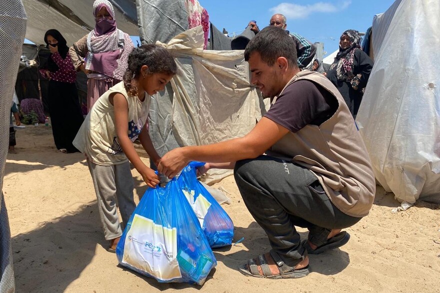 Helfer übergibt Hilfspaket an Mädchen im Gazastreifen