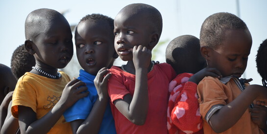 Spielende Kinder in Kenia halten sich an den Schultern fest