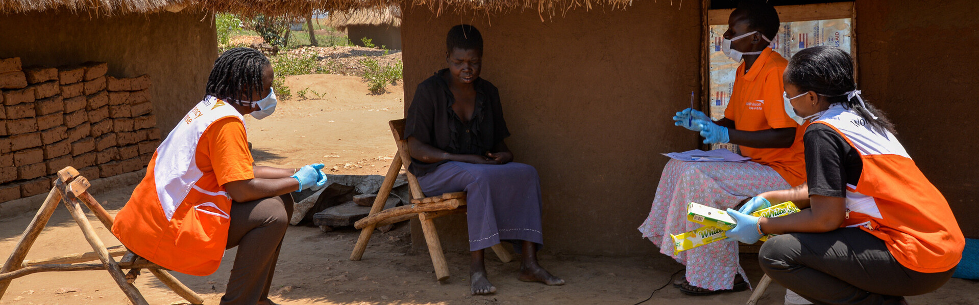 Helferinnen von CARE klären eine Dorfbewohnerin in Uganda über das Corona-Virus auf