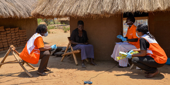 Helferinnen von CARE klären eine Dorfbewohnerin in Uganda über das Corona-Virus auf