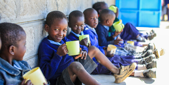 Schulkinder in Kenia halten einen Trinkbecher in der Hand