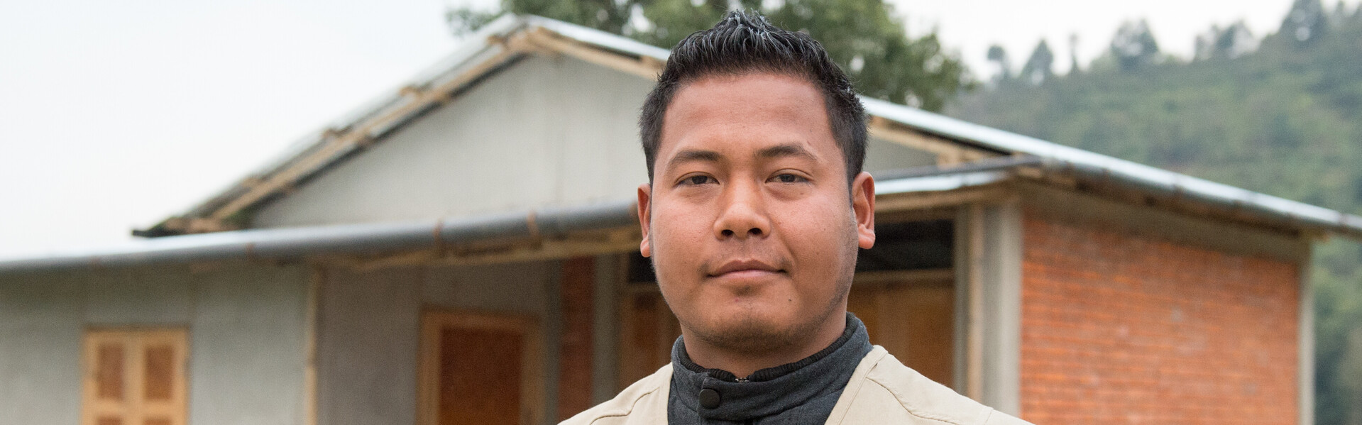 Ein Mitarbeiter der Organisation Habitat for Humanity steht vor einem Musterhaus, das nach dem Erdbeben in Nepal erbaut wurde.