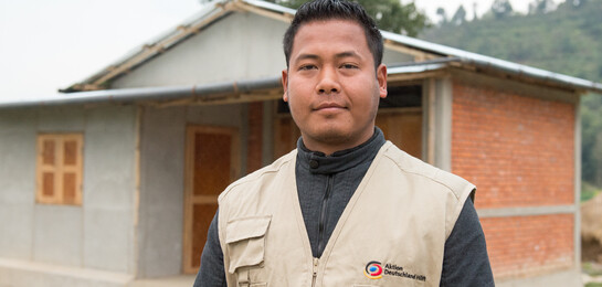 Ein Mitarbeiter der Organisation Habitat for Humanity steht vor einem Musterhaus, das nach dem Erdbeben in Nepal erbaut wurde.
