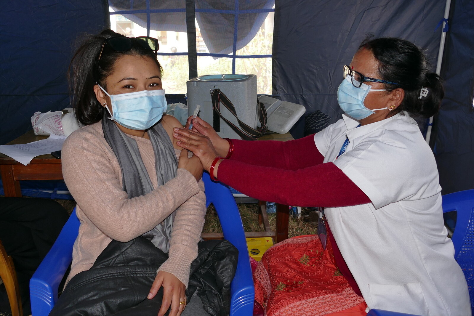 Eine Helferin impft eine Frau in Nepal gegen Covid-19