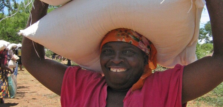 Eine Frau in Simbabwe trägt Säcke auf ihren Kopf, Copyright Help - Hilfe zur Selbsthilfe Eine Frau in Simbabwe trägt Säcke auf ihren Kopf