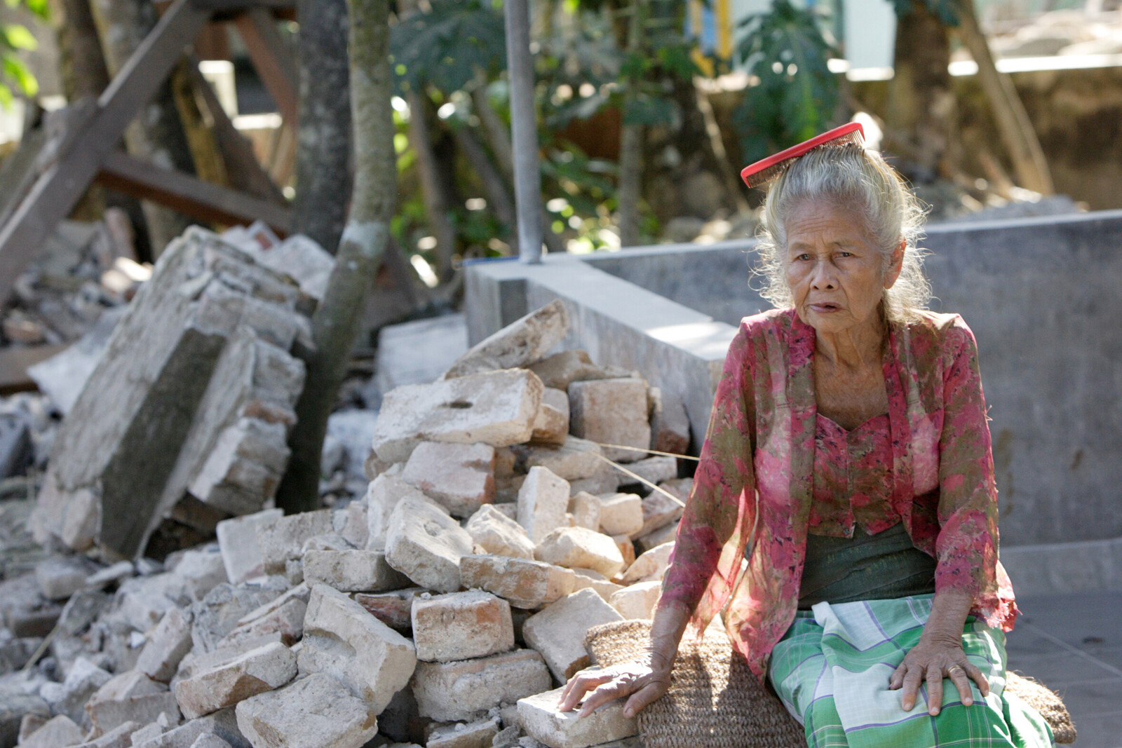 Eine alte Frau sitzt auf den Trümmern eines Hauses, das beim Erdbeben zerstört wurde