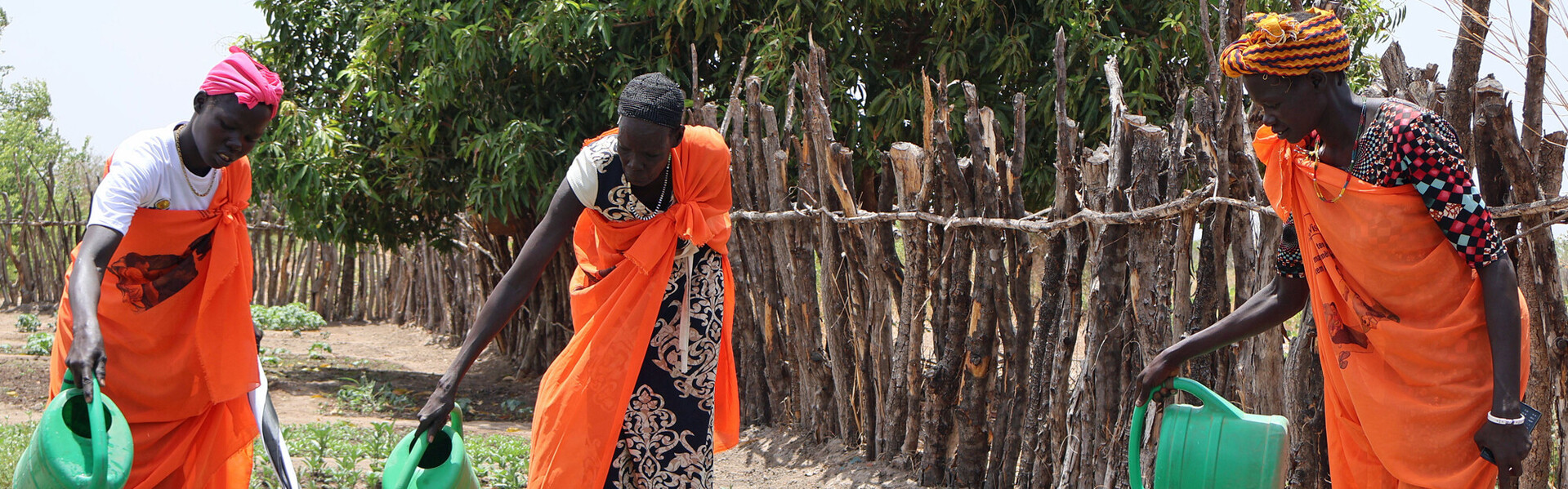 Zwei Frauen im Südsudan bewässern den Gemeinschaftsgarten der Matiei Primary Health Care Unit von World Vision 