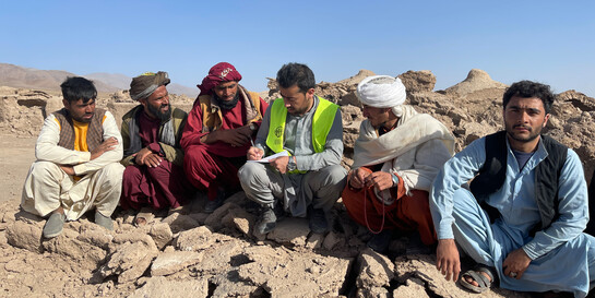 Eine Gruppe von Männern sitzt zwischen den Trümmern eingestürzter Gebäude nach einem Erdbeben und organisiert Hilfsmaßnahmen (Symbolbild)