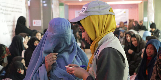 Eine Helferin spricht mit einer Frau, die eine Burka trägt, Copyright Help – Hilfe zur Selbsthilfe