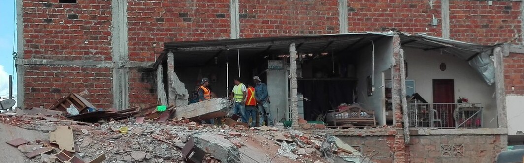 Helfer stehen nach dem Erdbeben in Ecuador vor einem zerstörten Haus