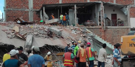 Helfer stehen nach dem Erdbeben in Ecuador vor einem zerstörten Haus
