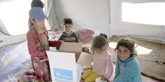 Kinder in einem Lager für Geflüchtete in Idlib, Syrien, packen im Sommer 2019 neugierig ihr Lebensmittelpaket aus