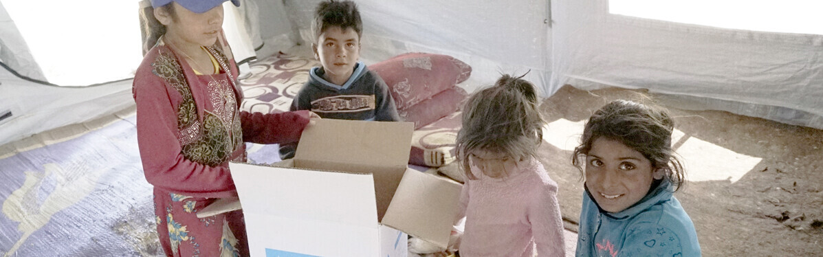 Kinder in einem Lager für Geflüchtete in Idlib, Syrien, packen im Sommer 2019 neugierig ihr Lebensmittelpaket aus