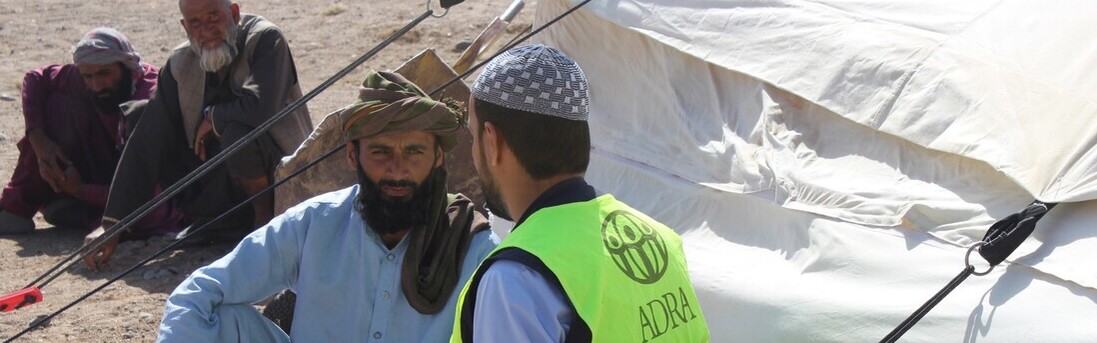 ADRA fordert konkrete Maßnahmen für die Sicherheit humanitärer Helfer Ein humanitärer Helfer unterhält sich mit einem Mann vor einer Notunterkunft in Afghanistan