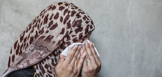 Frau trauert vor einer Wand in Aleppo, Syrien