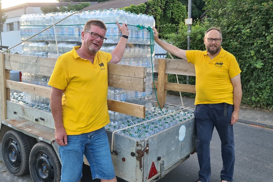 Helfer unserer Bündnisorganisation Help - Hilfe zur Selbsthilfe verteilen Trinkwasser in Hochwassergebieten