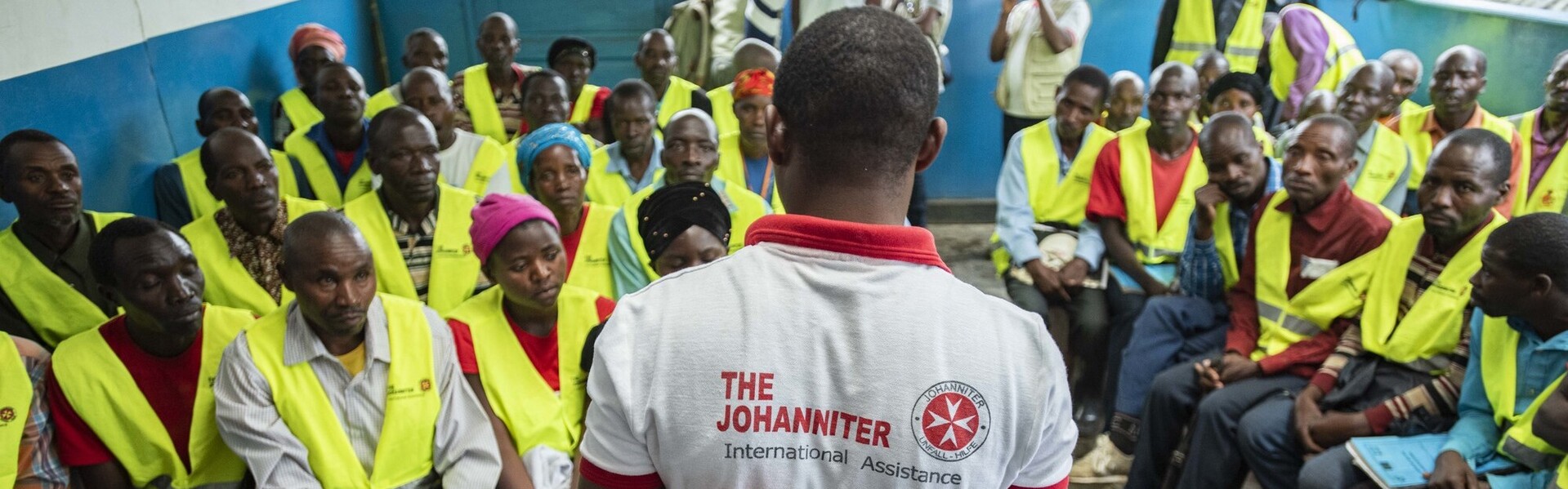 Ein Helfer der Johanniter spricht vor einer Gruppe von Menschen im Kongo