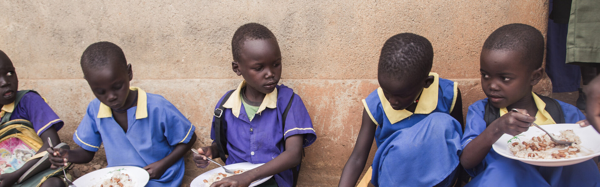 Im Südsudan sitzen Kinder vor einer Schule und essen