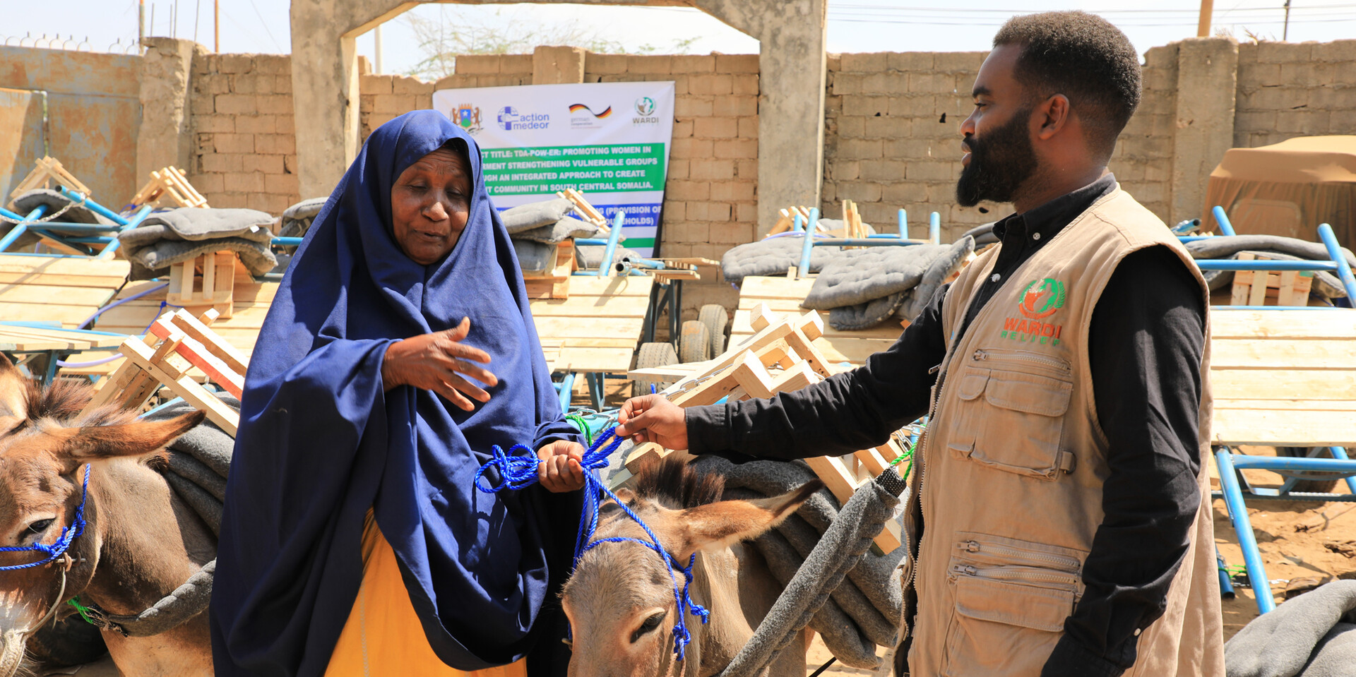 Neben Schulungen in klimaangepasster Landwirtschaft erhalten frauengeführte Haushalte auch neues Vieh Ein Helfer einer gemeinnützigen Organisation überreicht einer Frau in Somalia einen Esel